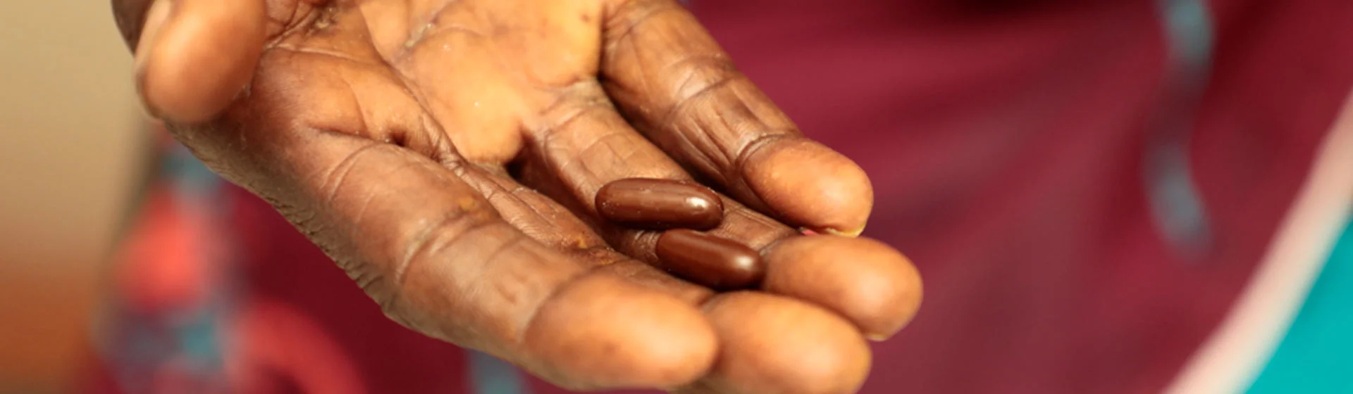 hand holding two brown capsules.